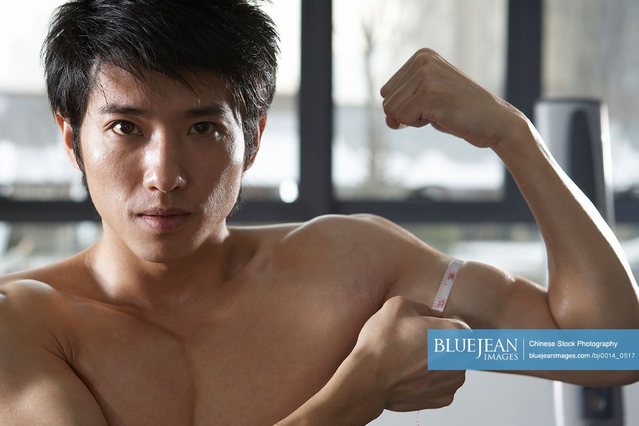 Young Chinese man measuring muscles at the gym