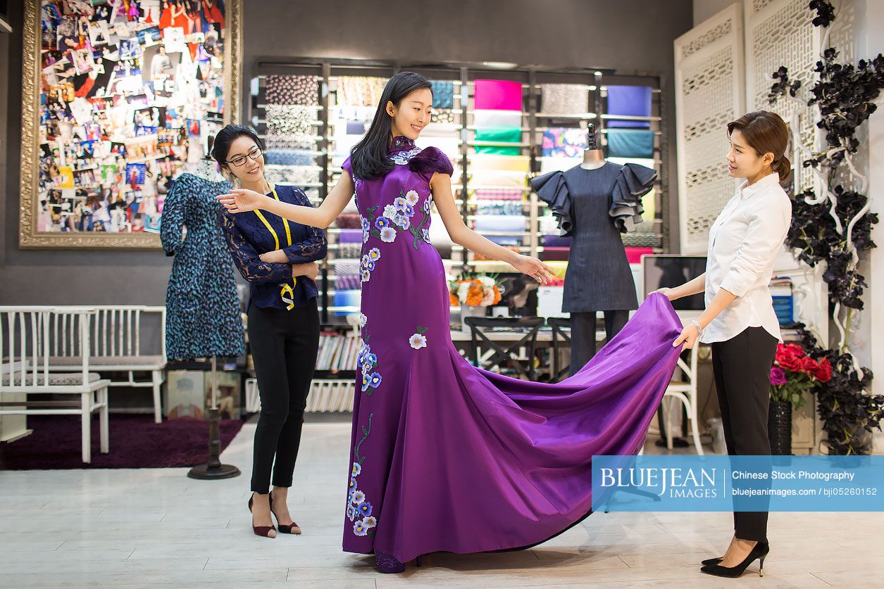 Chinese fashion designers examining dress on customer