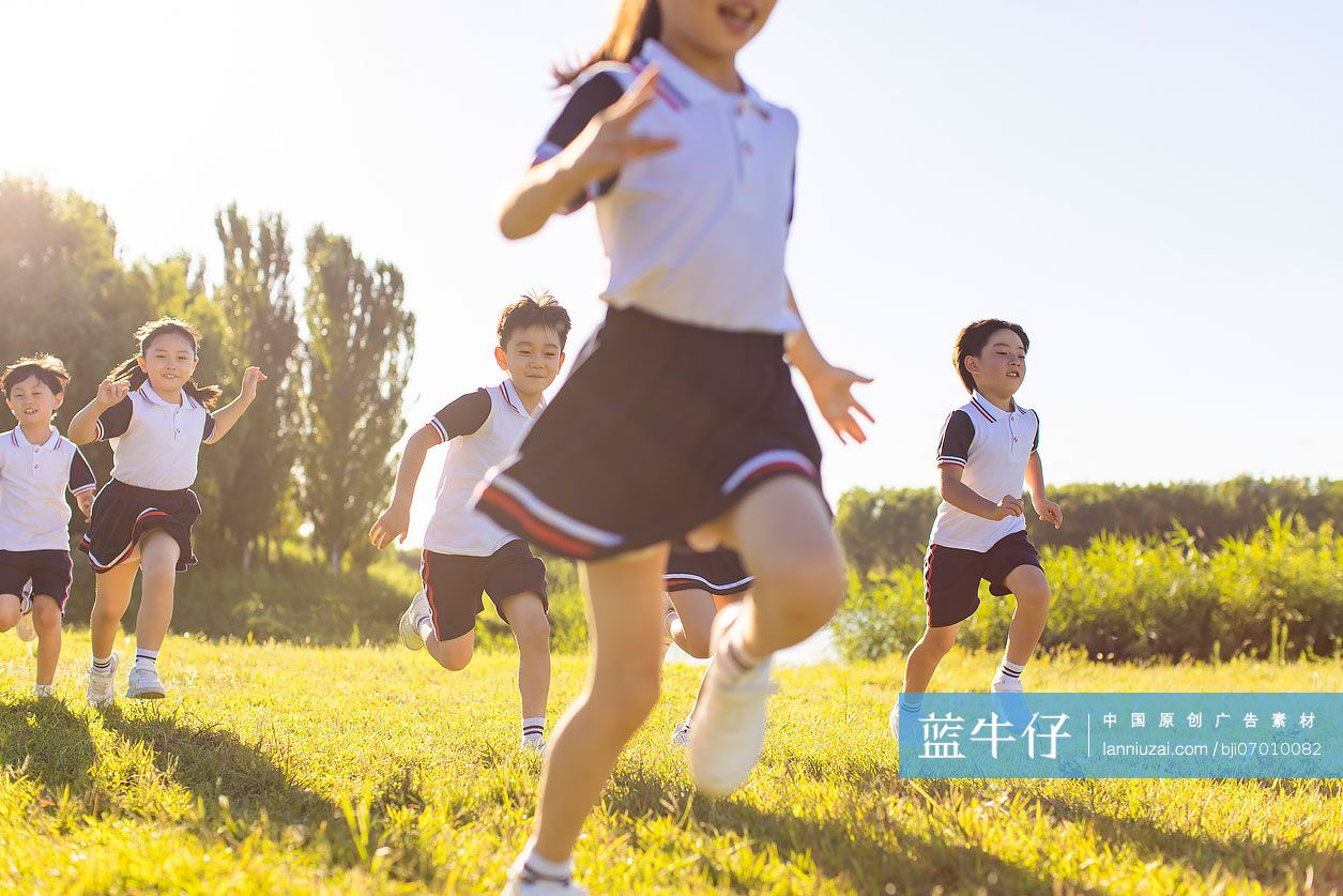快乐的小学生在草地上奔跑