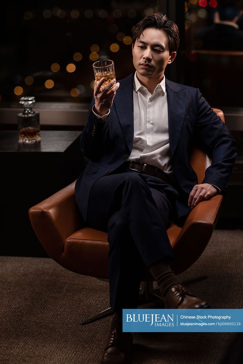 Elegant Chinese man drinking whiskey