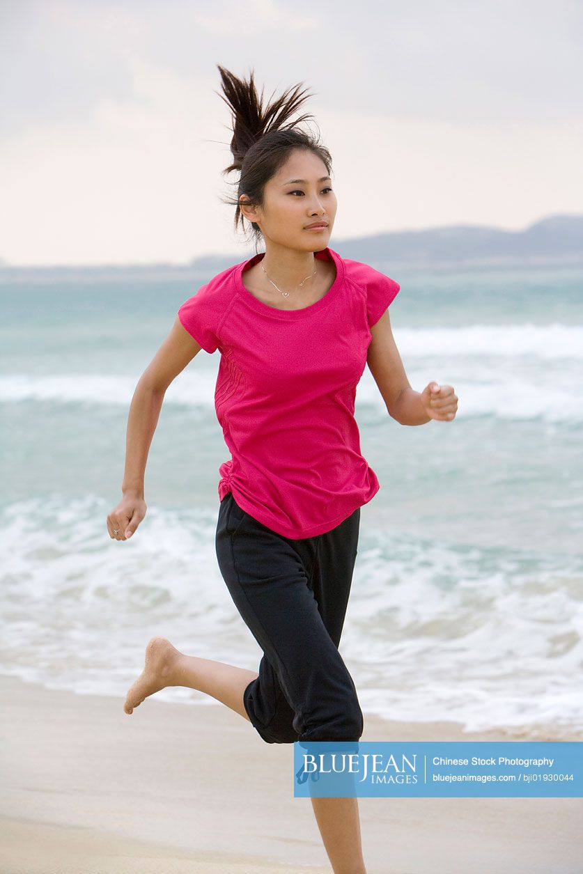 Young Chinese woman running on the beach