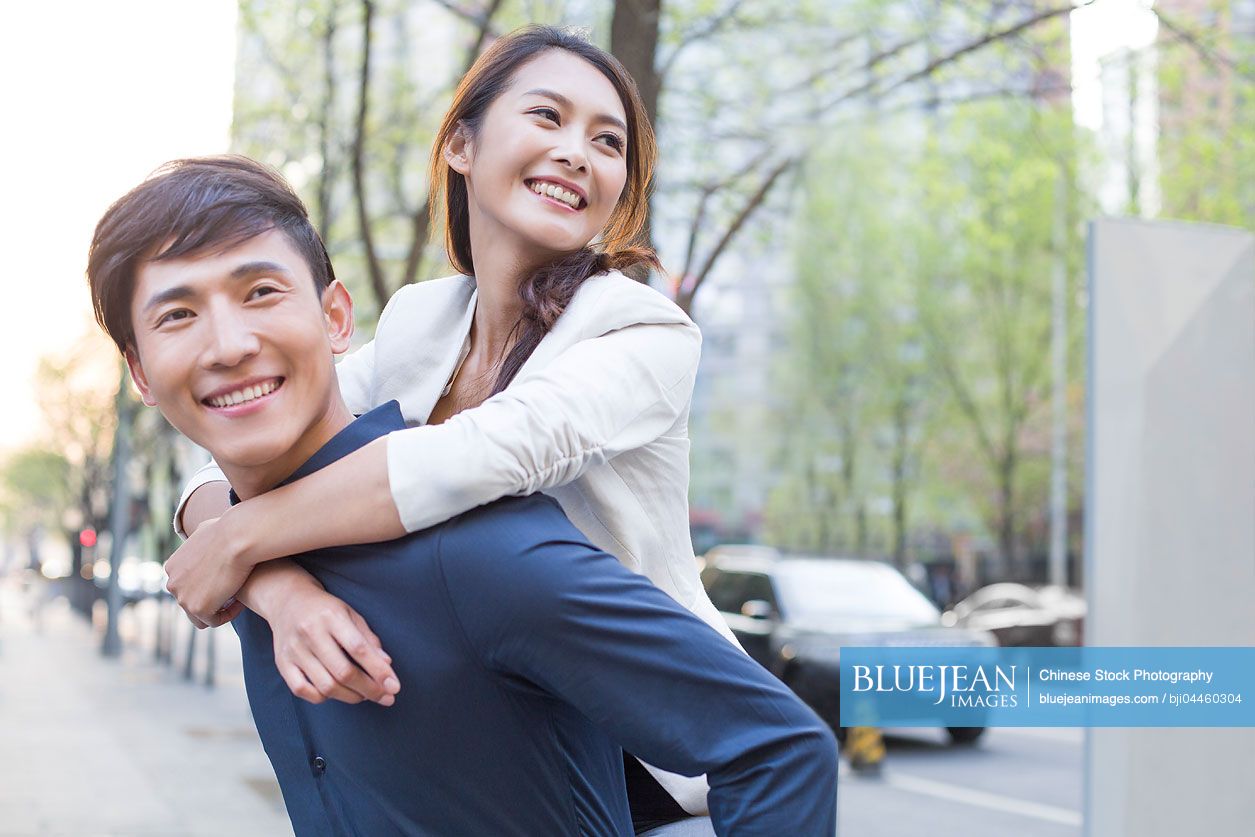 Young Chinese man piggybacking girlfriend