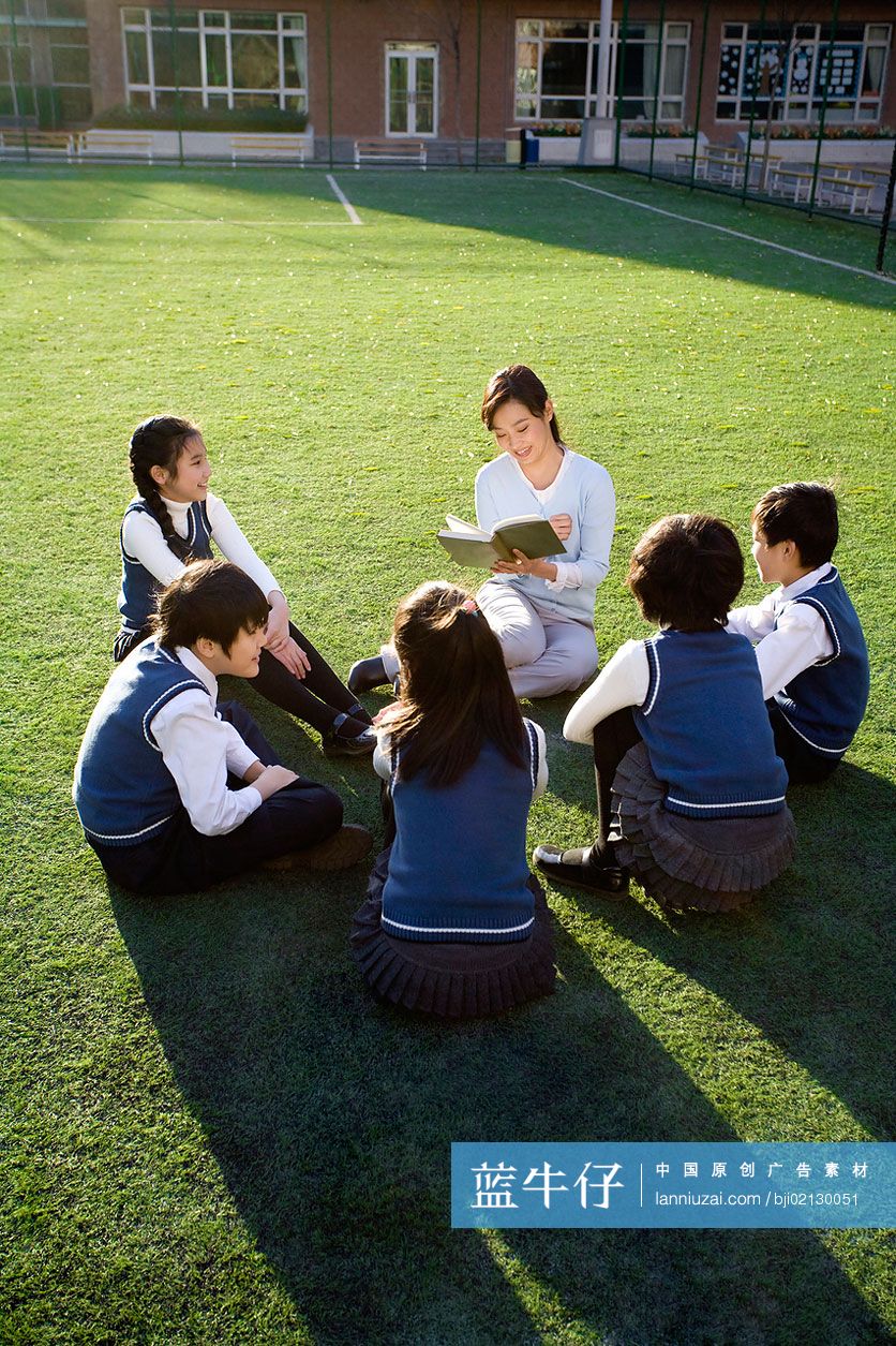 小学生在草地上围着老师学习