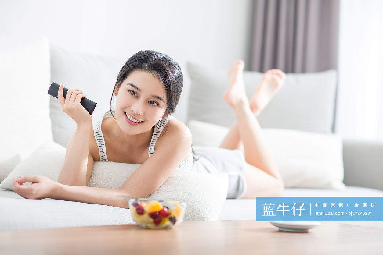 年轻女子在沙发上看电视