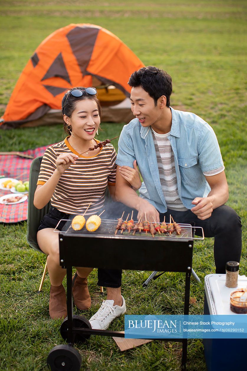 Happy young Chinese couple barbecuing outdoors