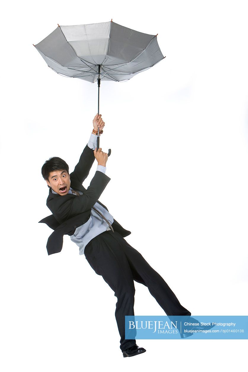 Young chinese businessman dropping down by umbrella high res stock