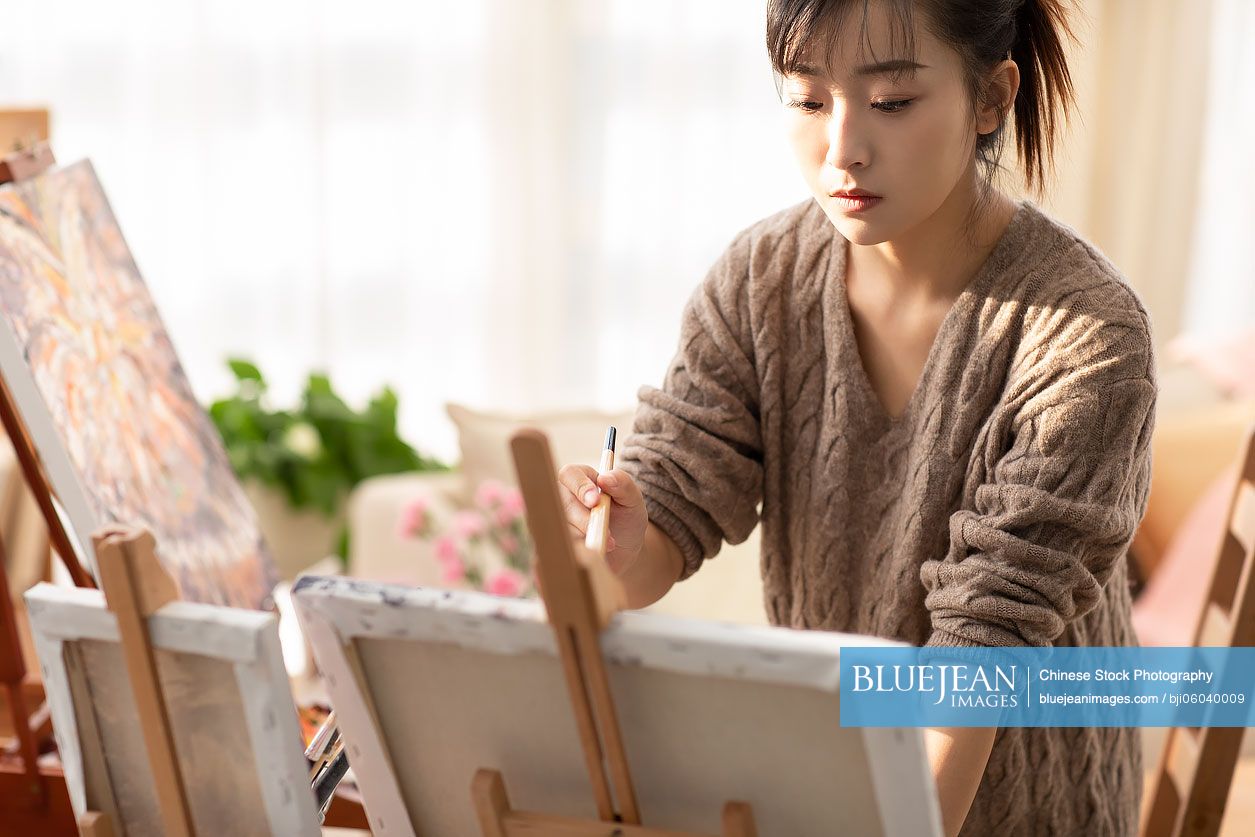 Young Chinese woman painting at home