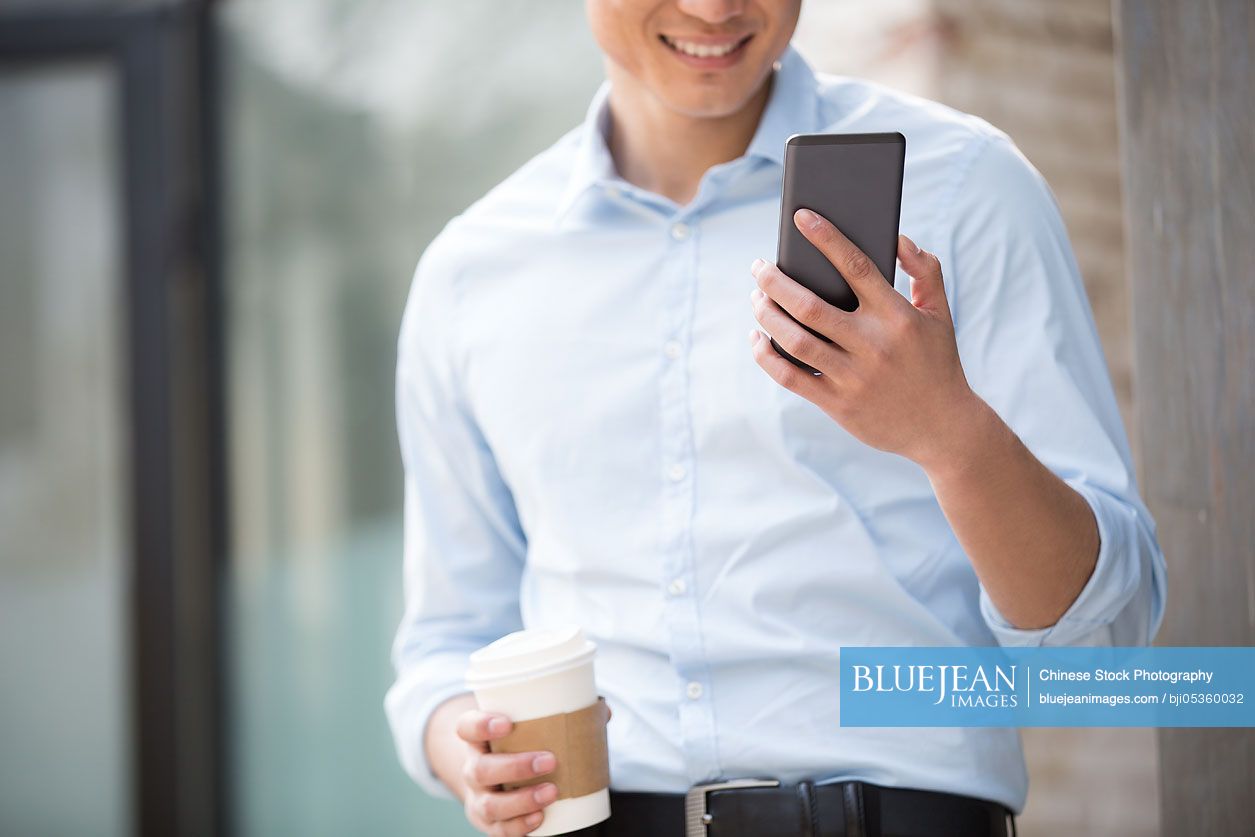 Young Chinese businessman with smart phone and coffee