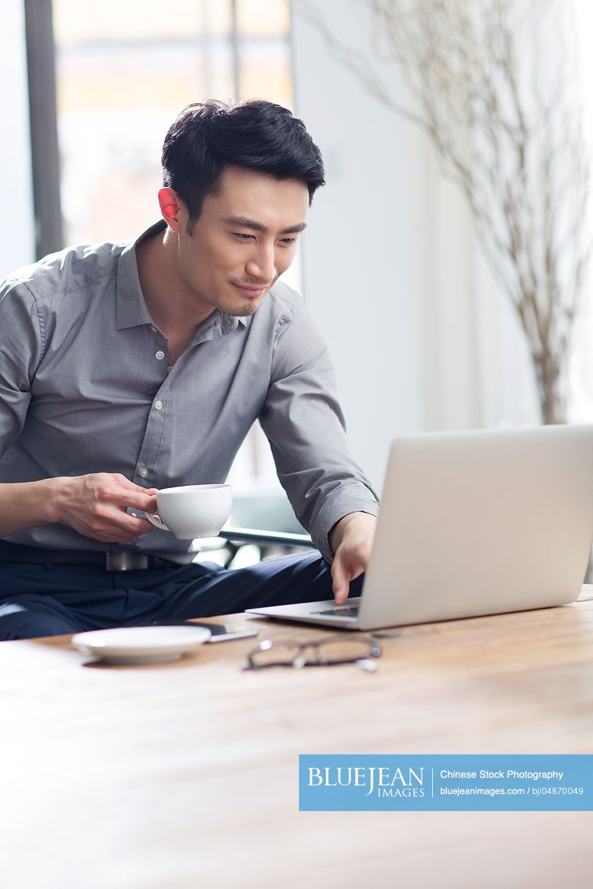 Young Chinese man working with laptop in office