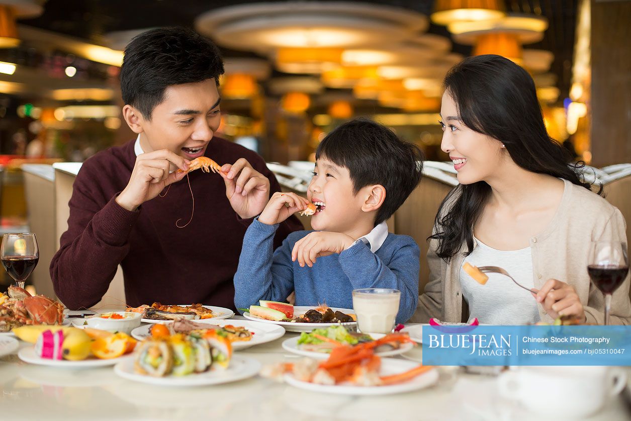 Cheerful young Chinese family having buffet dinner