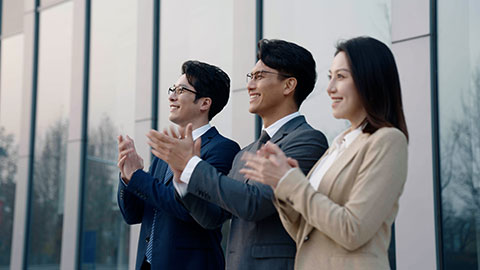 Cheerful Chinese business people applauding outdoors