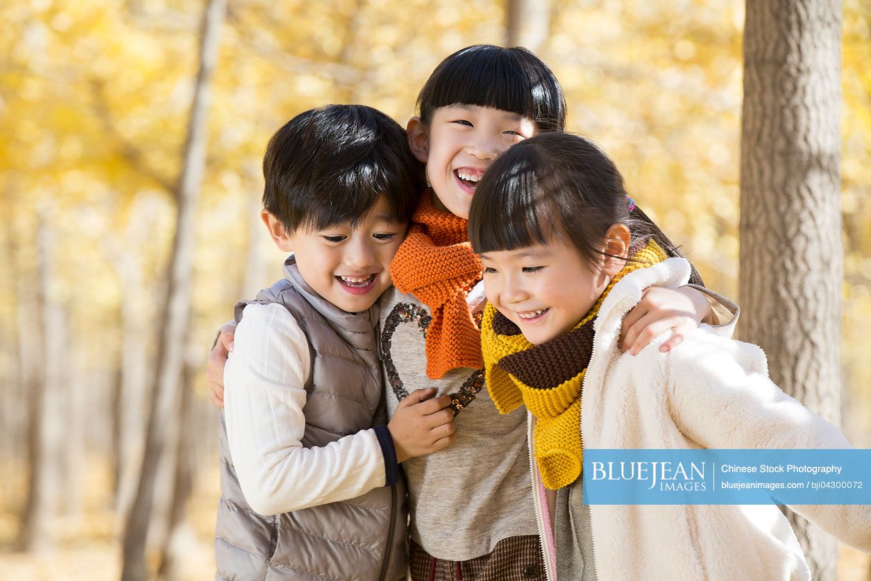 Three Chinese children playing in autumn woods